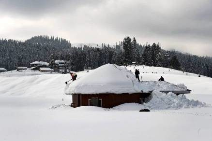 Labourers clearing snow from a hut after recent heavy snowfall at ski resort Gulmarg in of North Kashmir on Wednesday. 
