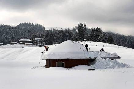 Click to enlarge Labourers clearing snow from a hut after recent heavy snowfall at ski resort Gulmarg in of North Kashmir on Wednesday.