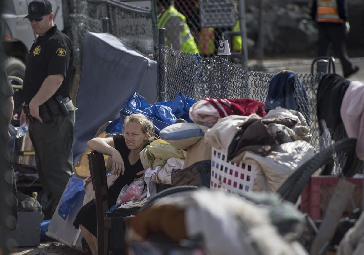 Homeless woman near fence at Santa Ana homeless encampment