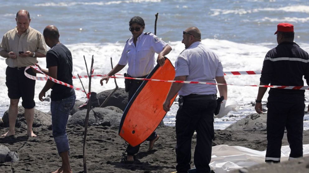 A policewoman holds the bodyboard of Alexandre Naussance, who was killed by a shark