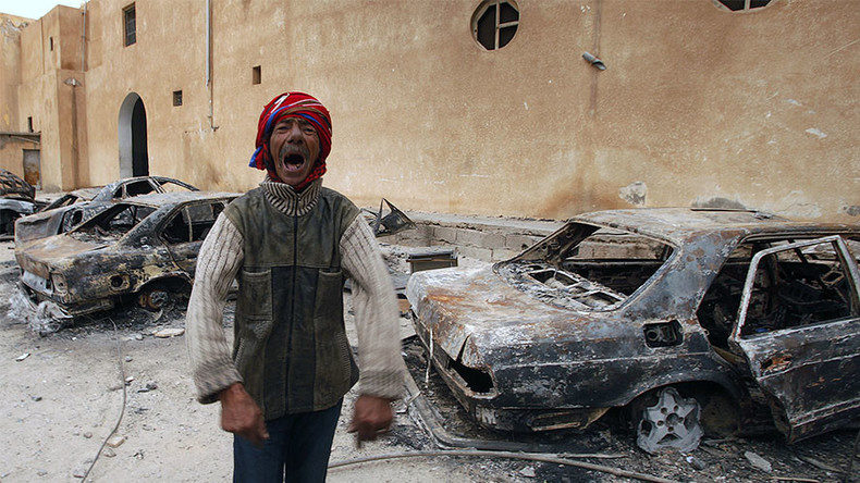 A man gestures in front of burnt vehicles in a state security building in Tobruk, east of LibyaA man gestures in front of burnt vehicles in a state security building in Tobruk, east of Libya