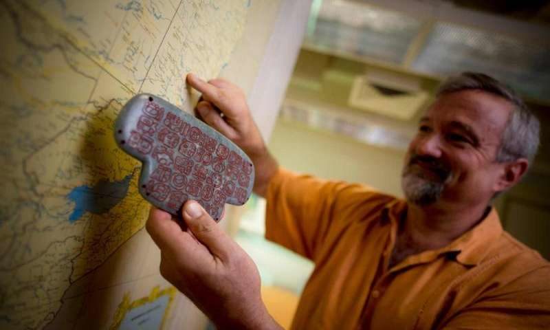 UC San Diego archaeologist Geoffrey Braswell holds a replica of the Maya jade pendant