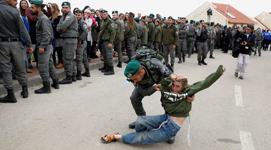 An Israeli border policeman removes a pro-settlement activist