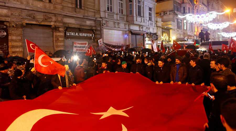 People wave Turkish flags during a protest in front of the Dutch Consulate in Istanbul