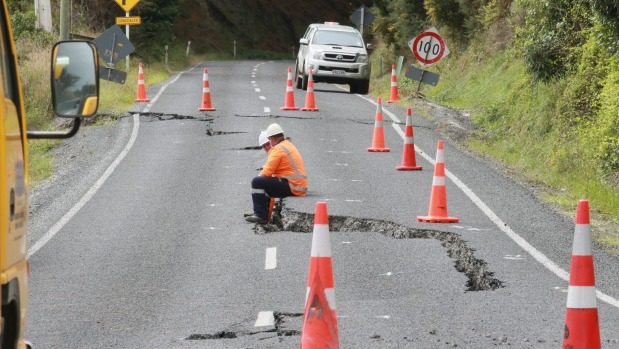 Contractors take a seat while assessing the damage on a road near the slip