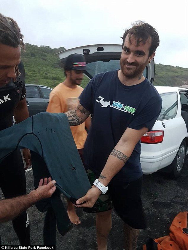 Click to enlarge Mr Fernandez posed with the wetsuit showing the puncture marks from the unknown shark