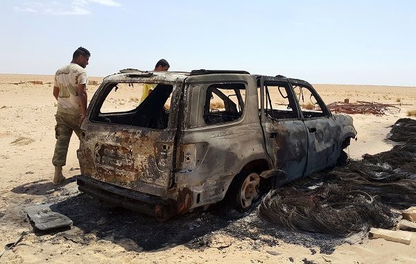 Men inspect the wreckage of a vehicle