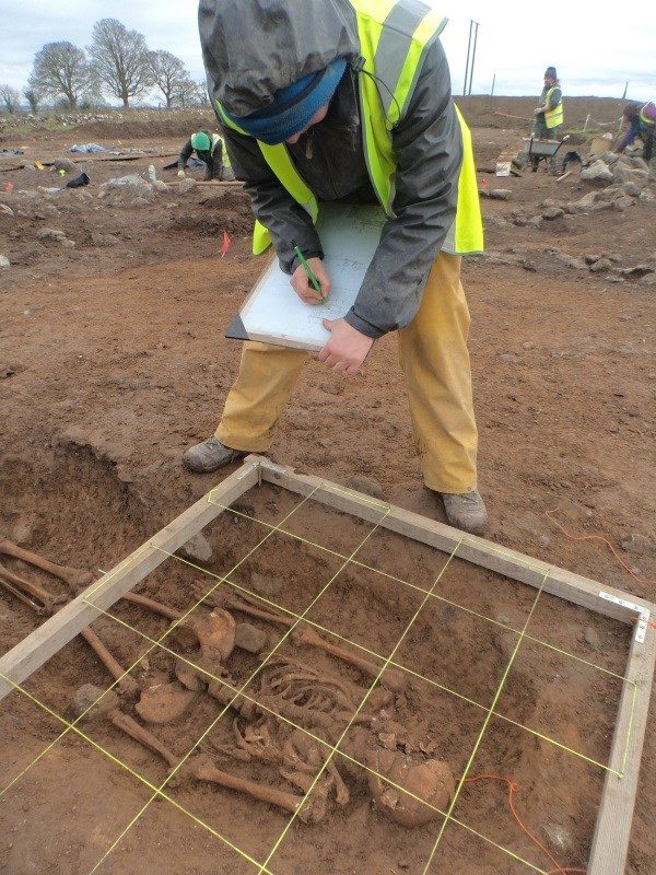 Click to enlarge archaeologist recording a human skeleton