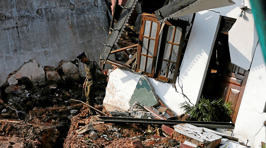 A police officer inspects a damaged house for victims during a rescue mission after a garabage dump collapsed and buried dozens of houses in Colombo, Sri Lanka