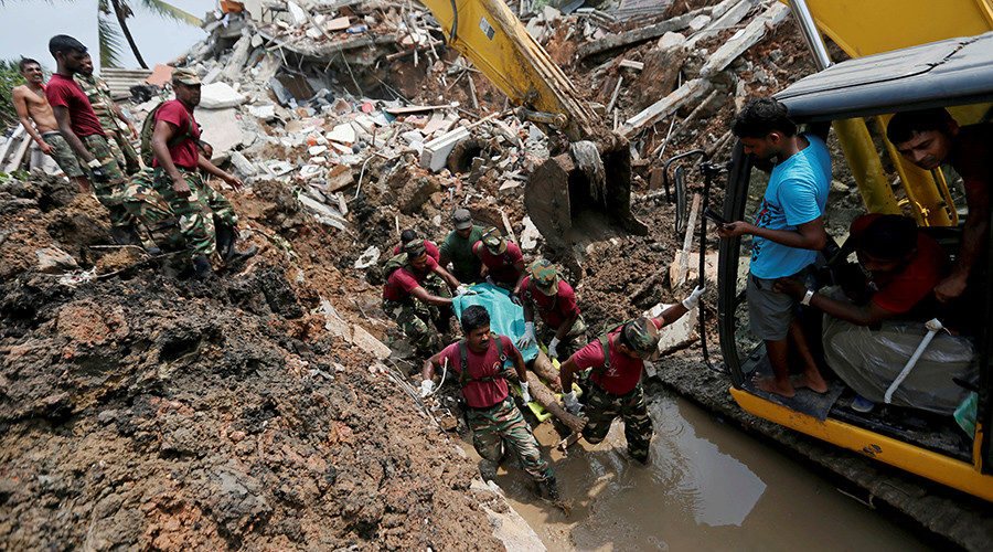 Members of the military carry a dead victim during a rescue mission after a garbage dump collapsed and buried dozens of houses in Colombo, Sri Lanka