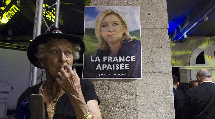 woman in front of Marine Le Pen election poster