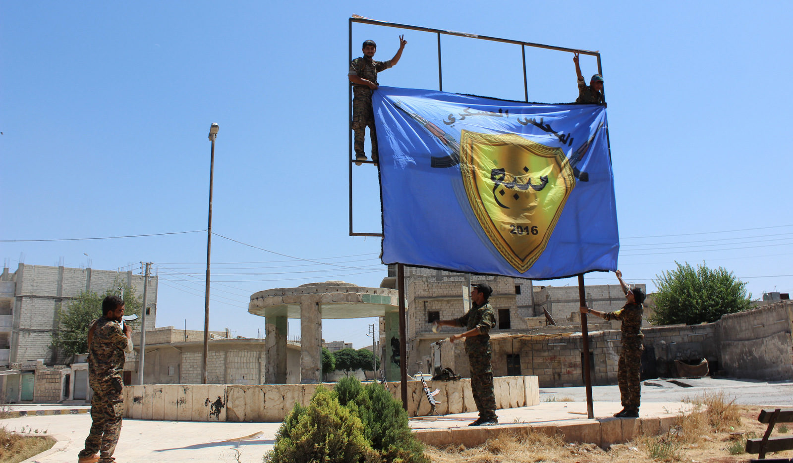 U.S.-backed, Kurdish-led Syria Democratic Forces raise their flag in the center of the town of Manbij after driving ISIS out of the area, in Aleppo province, Syria