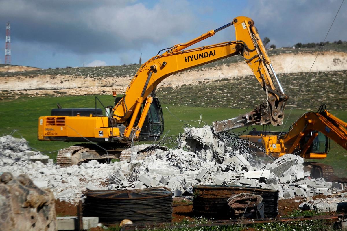An Israeli bulldozer demolishes a Palestinian house