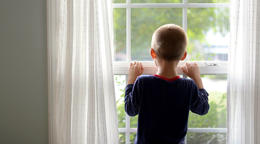 Young boy looking out window