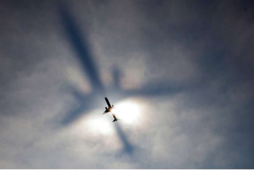 The shadow of an air liner penetrates a layer of fog, Logan Airport, Boston