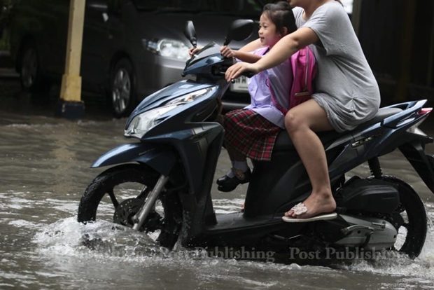 A mother and her daughter ride through a flooded street by to get to school. Many areas of Bangkok were flooded following heavy rain in the early hours.