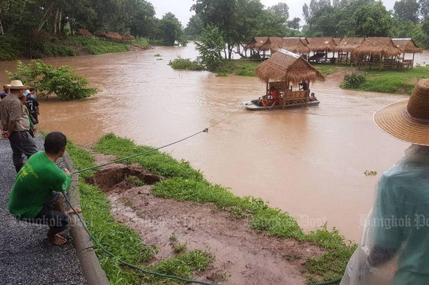 Residents try to stop a restaurant's straw huts from floating away in the swollen Kwai Noi River in Wat Bot district of Phitsanulok on Wednesday.