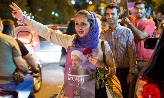 A woman holds a poster of Iranian President Hassan Rouhani during a campaign rally in Tehran