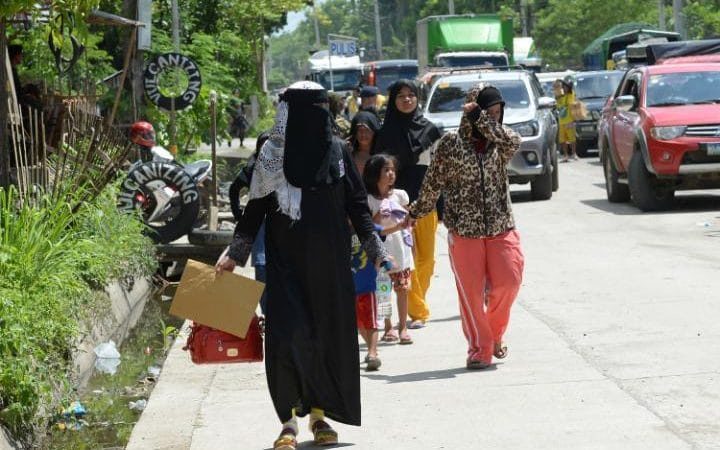 Residents fleeing from Marawi, where gunmen who had declared allegiance to the Islamic State group rampaged through the southern city, walk past a checkpoint at the entrance to Iligan on the southern Philippine island of Mindanao