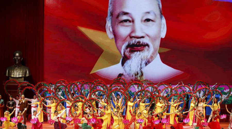 Artists perform in front of a giant screen showing Vietnam's late revolutionary leader Ho Chi Minh