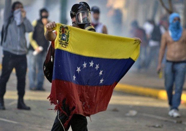 venezuelan holding flag and gas mask
