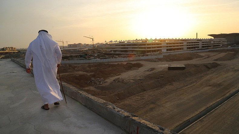 Click to enlarge man walks past construction in Qatar