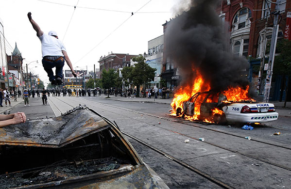 Protester jumps on burnt-out police care