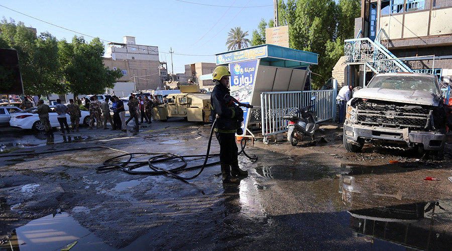 A firefighter hoses down a street after a suicide bomb attack in the city of Kerbala