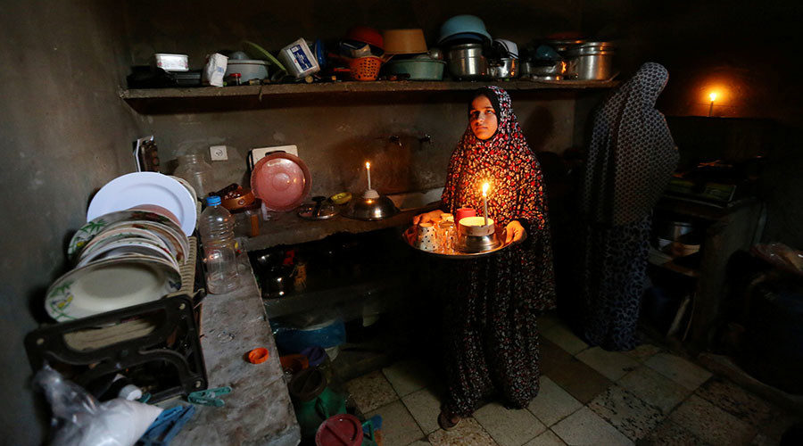 Palestinians prepare food at the kitchen of their house during a power cut in Khan Younis