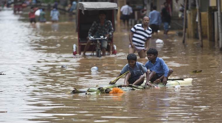 Children on a makeshift raft make their way through a flood waterlogged road in Guwahati. 