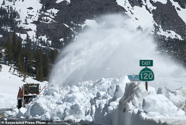 Crews feverishly blowing snow off the road in early June as they ready for the first summer visitors