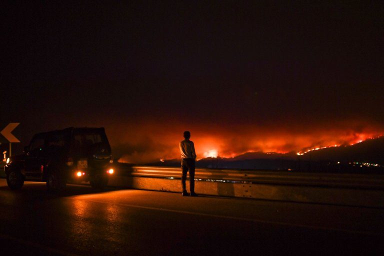 Click to enlarge A man stands on the roadside watching a wildfire at Anciao, Leiria