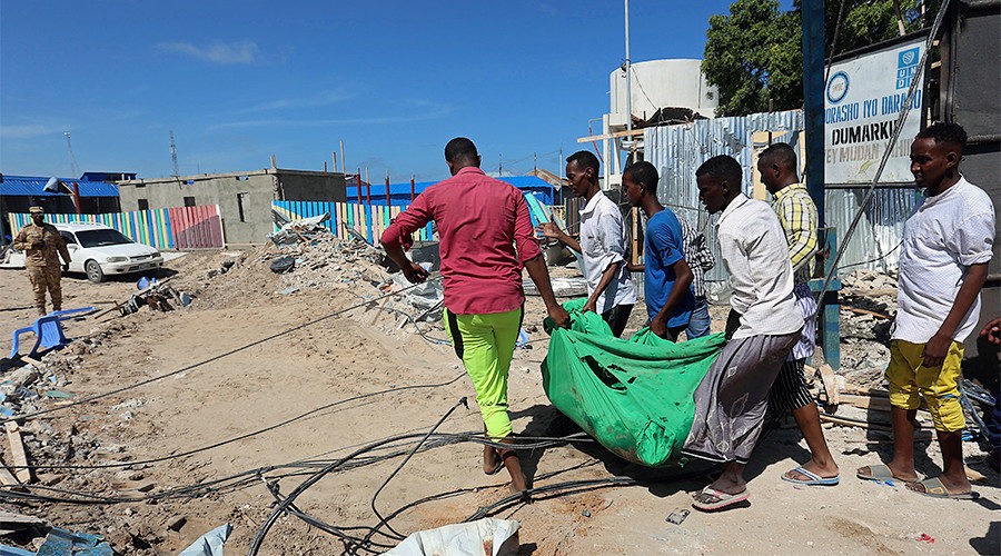 Click to enlarge Civilians carry the dead body of an unidentified man killed during an attack on a government building in Mogadishu