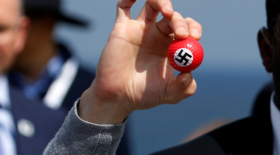 protester holds up golf balls with a swastika