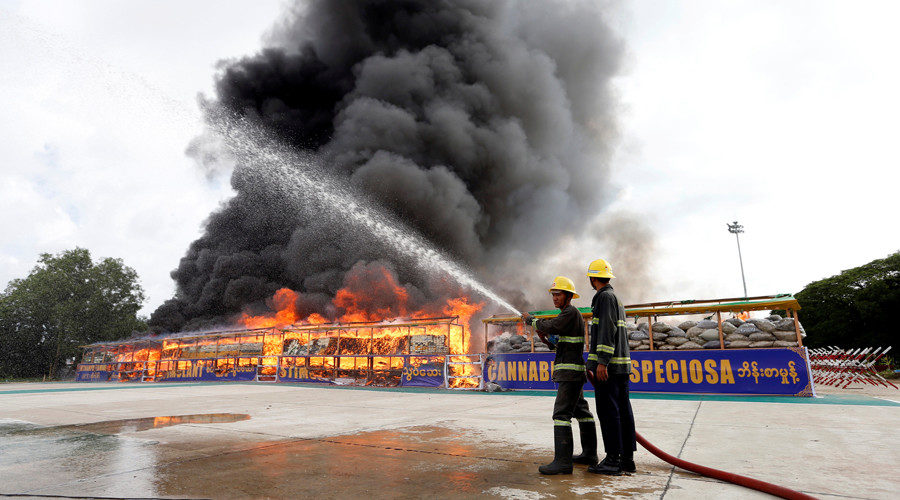 Firefighters prepare to extinguish fire after burning seized drugs outside Yangon, Myanmar