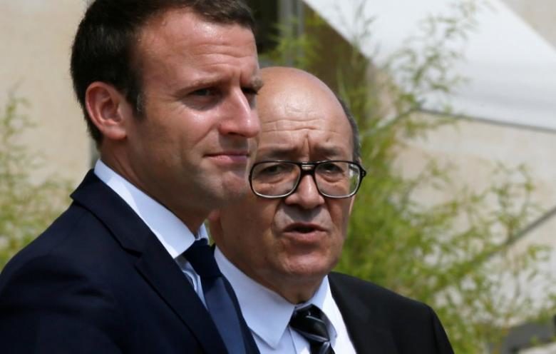 Emmanuel Macron walks next to Foreign Minister Jean-Yves Le Drian