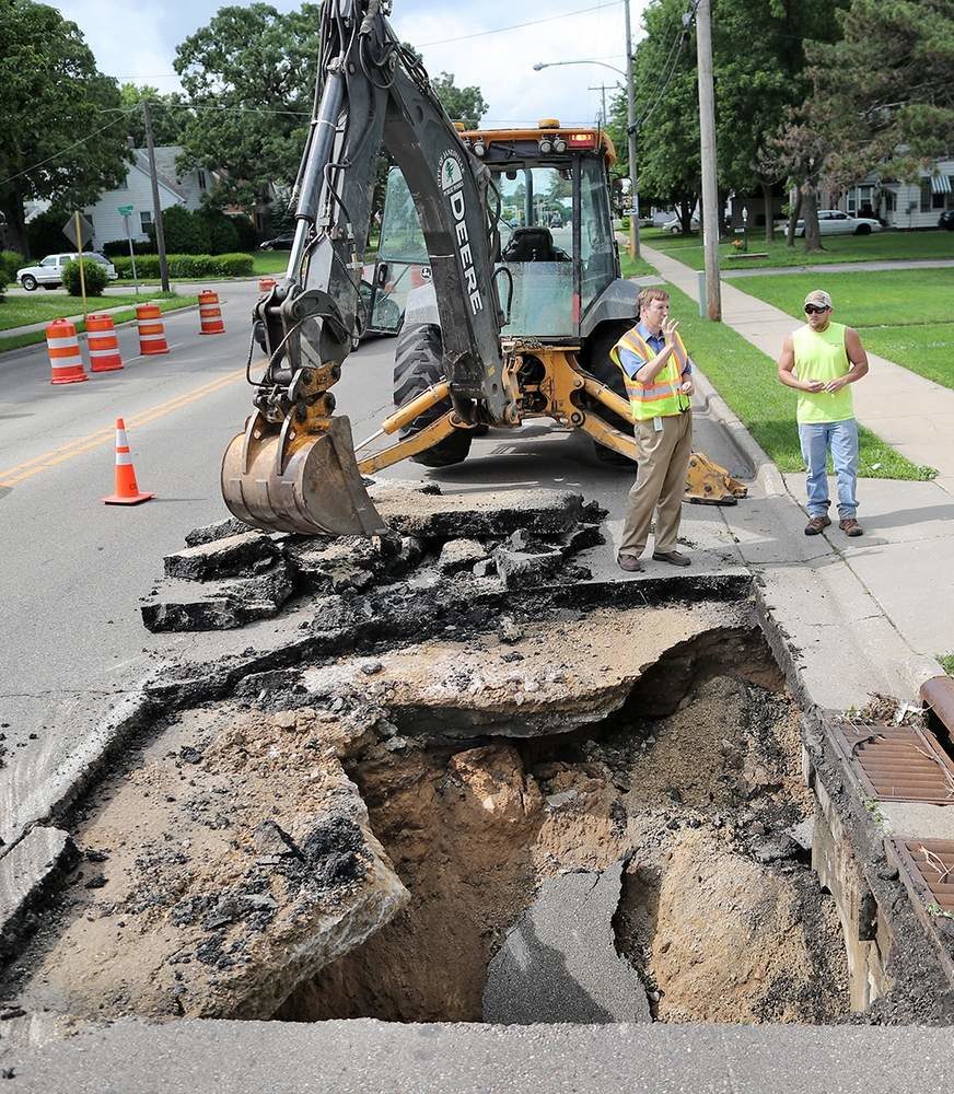 City of Janesville Department of Public works officials and crews discuss a sinkhole that opened up on North Washington Street in Janesville on Friday afternoon.