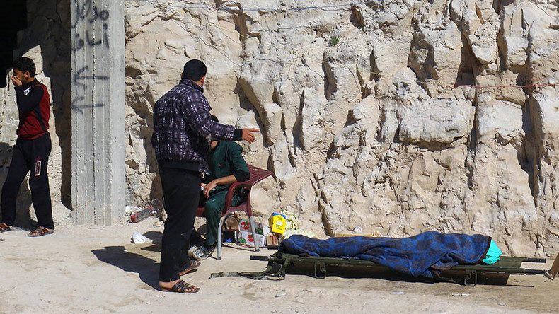 People stand near a dead body, described by rescue workers as a suspected gas attack victim