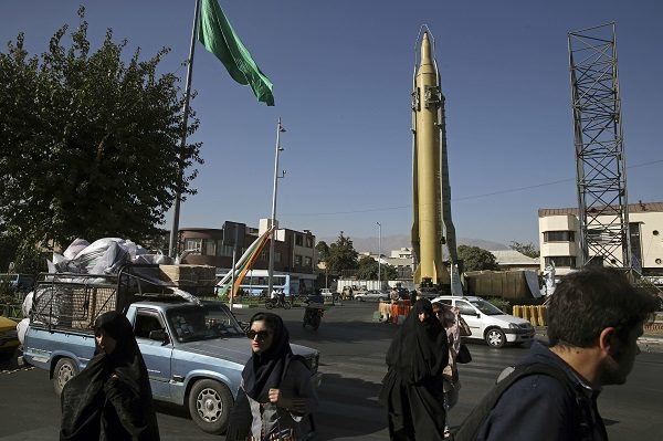 Iranians walk past a Ghadr-F missile