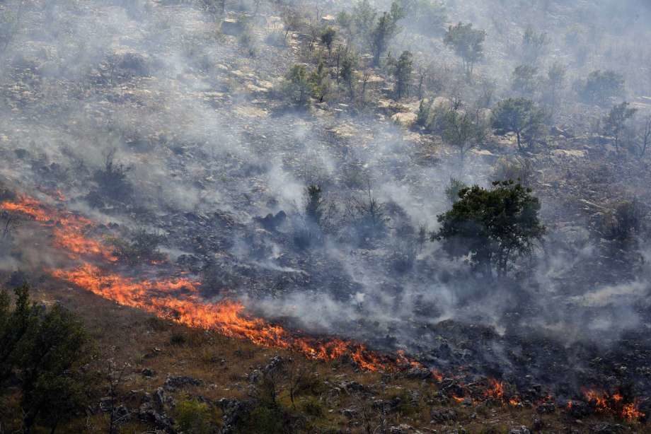 Smoke rises from trees burned by wildfire on a mountain near Montenegro capital Podgorica, Monday