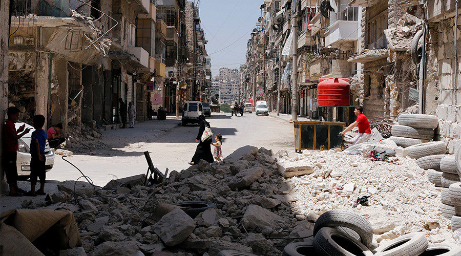 A woman walks with a child amid rubble at Bustan al-Qasr neighbourhood in Aleppo