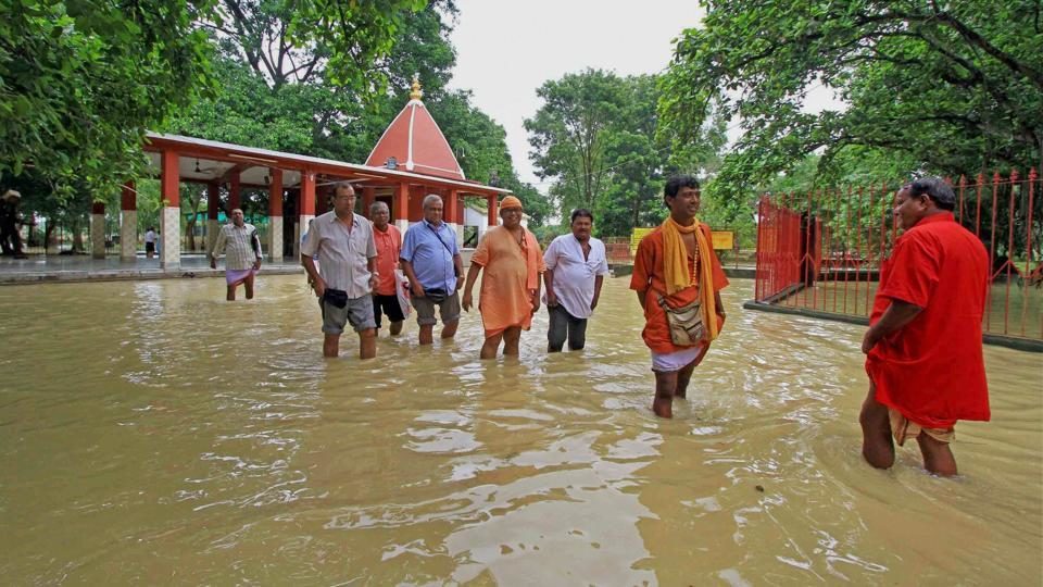 Devotees and a priest wade through floodwaters of Kopai river near a half-submerged Kankali Kali Temple in Birbhum district on Saturday.