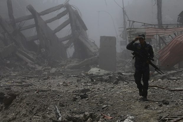 An Iraqi soldier walks through the ruins of Mosul