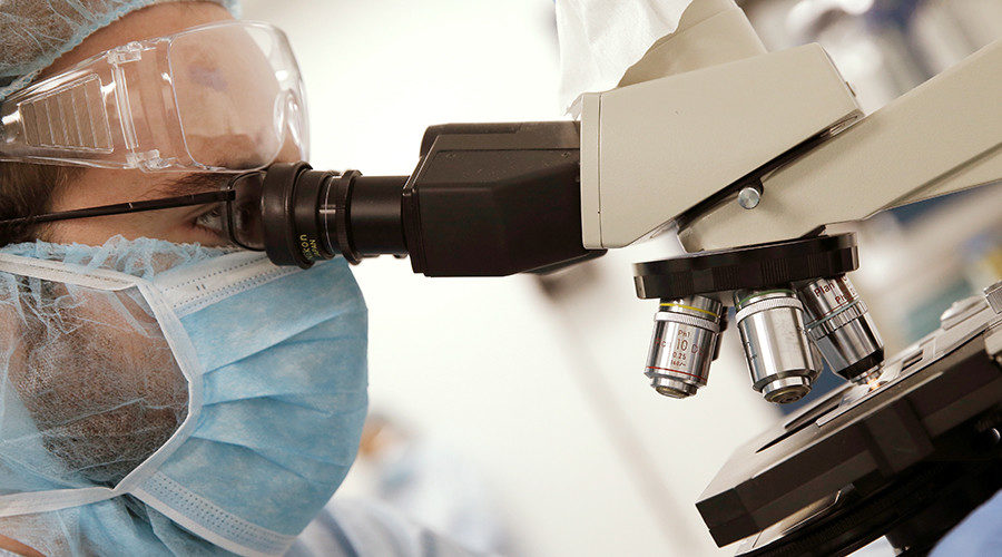 Click to enlarge Scientist looking into microscope