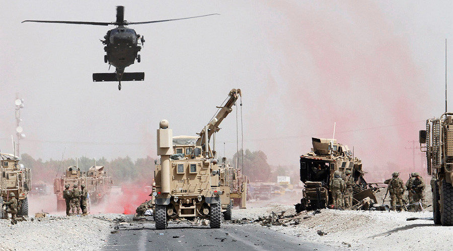 U.S. troops assess the damage to an armoured vehicle of NATO-led military coalition