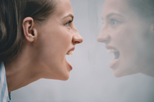 Angry woman yelling into a mirror