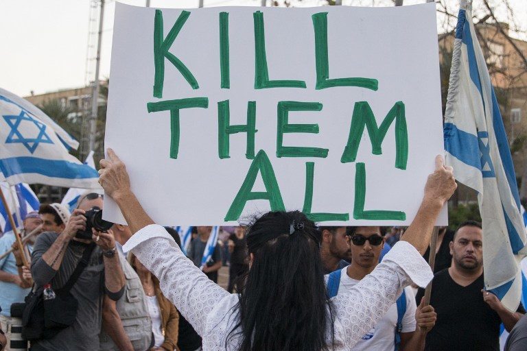 A woman holds up a sign 'Kill them all'