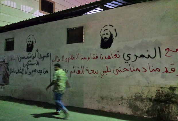 man passing images of executed Shiite cleric Nimr al-Nimr in the Awamiya