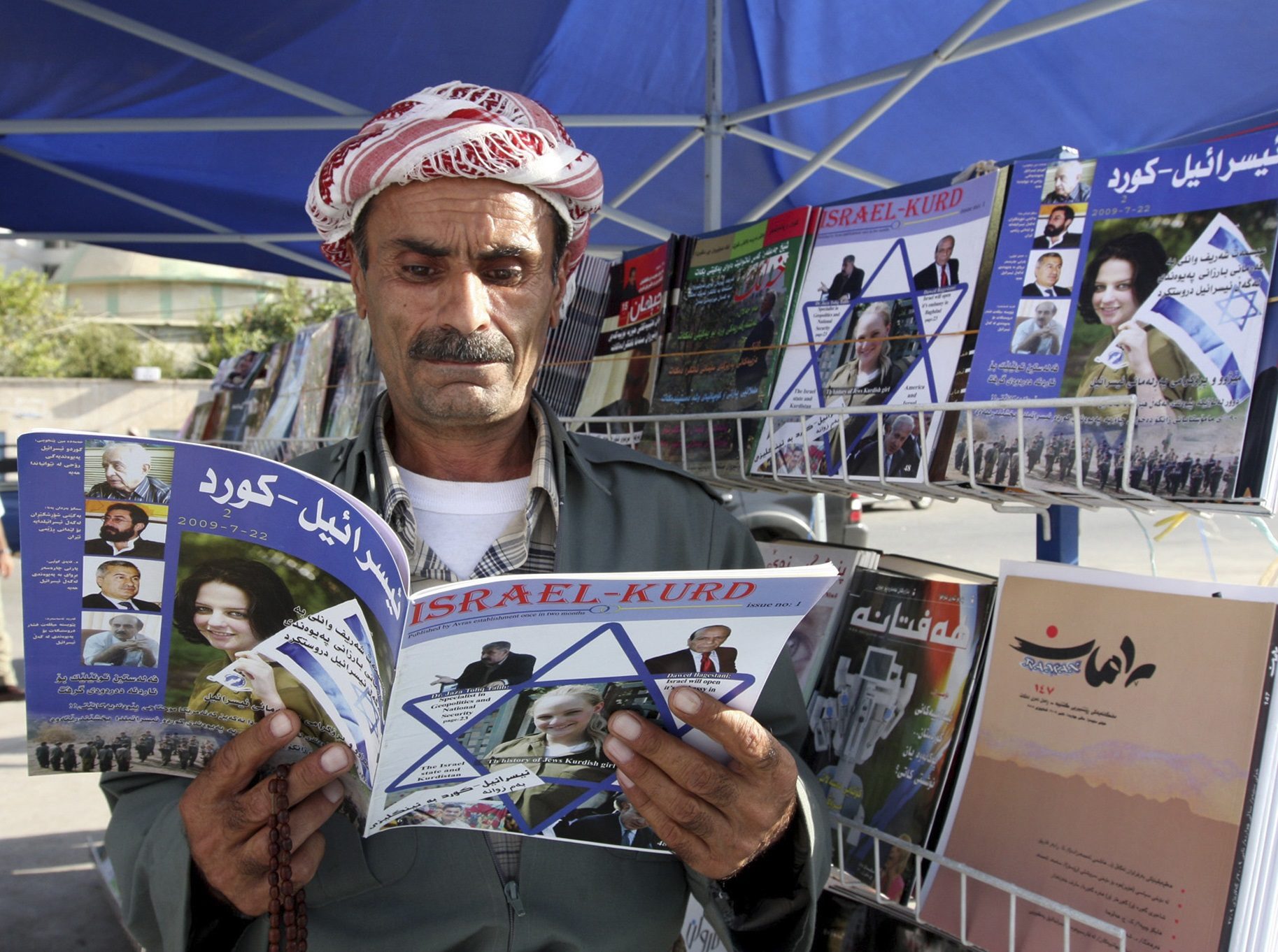 An Iraqi Kurd reads a copy of the magazine Israel-Kurd on a street in Irbil, Iraq