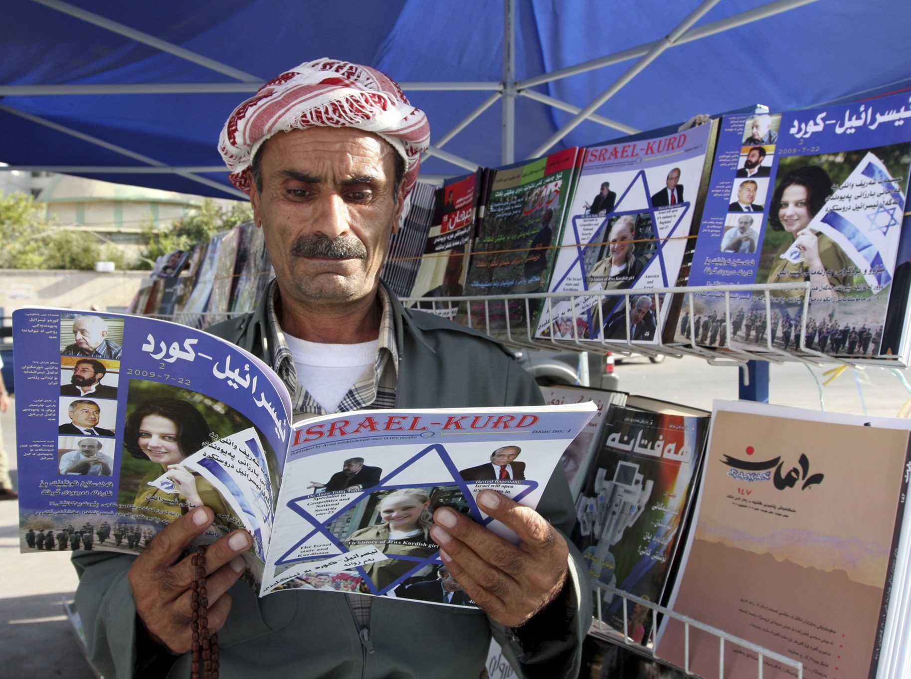 Click to enlarge An Iraqi Kurd reads a copy of the magazine Israel-Kurd on a street in Irbil, Iraq